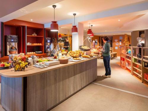 une femme debout à un comptoir dans une cuisine dans l'établissement IBIS STYLES Rouen Parc Expos Zenith, à Saint-Étienne-du-Rouvray