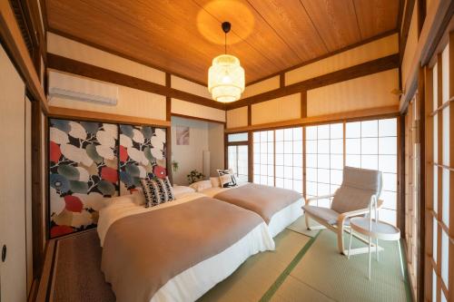 a bedroom with two beds and a chair in it at Thresora East Tokorozawa 池袋新宿アクセス良好 隠れ家一軒家 in Tokorozawa