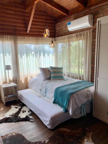 a bedroom with a bed in a room with windows at One Cabañas Malva in Los Antiguos