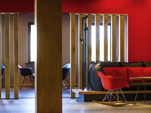 uma sala de estar com um sofá vermelho e cadeiras em ibis Hotel Brussels Airport em Diegem