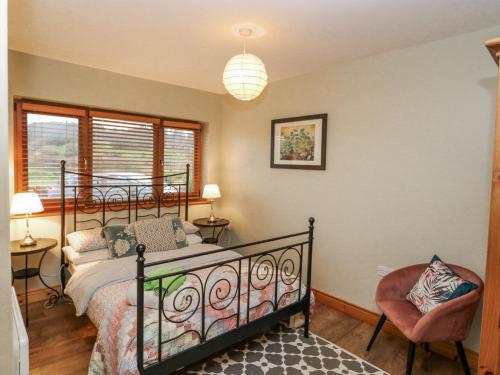 um quarto com uma cama e uma cadeira em Lough Cluhir Cottage em Myross