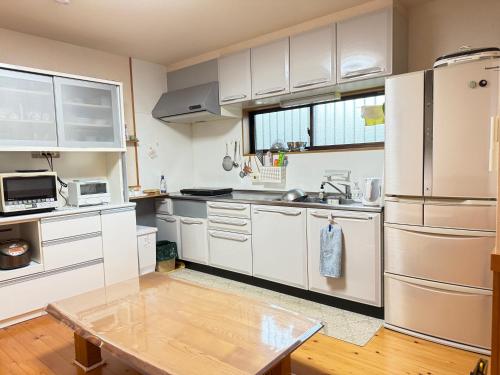 a kitchen with white cabinets and a stainless steel refrigerator at ゲストハウス道 Michi in Nachikatsuura