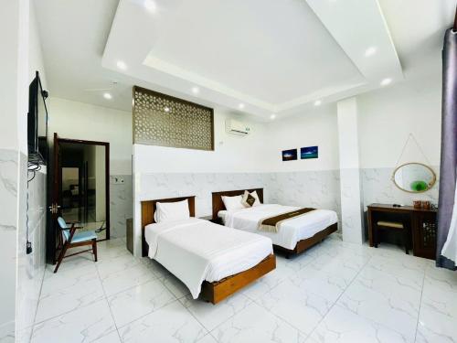 コンダオにあるHưng Khánh Hotelのベッド2台と机と鏡のある寝室