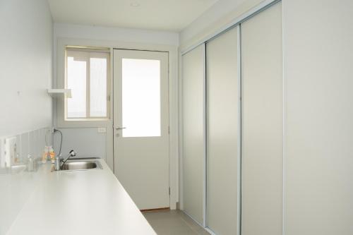 een witte keuken met een wastafel en een raam bij Alaaya in Wallan