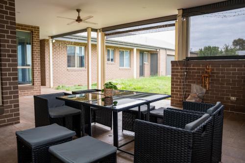 Un patio con una mesa de cristal y sillas. en Alaaya, en Wallan