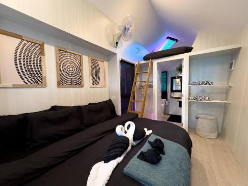 una sala de estar con un sofá negro y algunas toallas en Three Palms - Beach Front Tiny House by SP Villa, en Nathon Bay