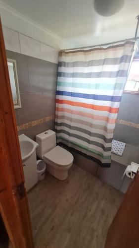 a bathroom with a toilet and a colorful shower curtain at CASA EN PALAFITO in El Quisco
