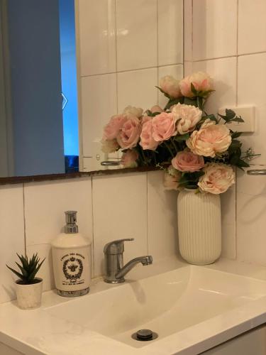 a bathroom sink with a vase of pink roses at Platform One Guildford in Guildford