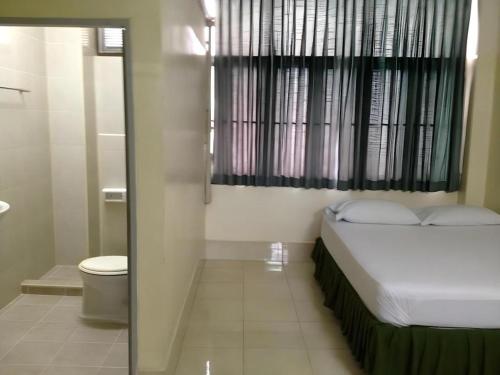 a small bedroom with a bed and a toilet at Numsin Hotel in Ban Rong Chang