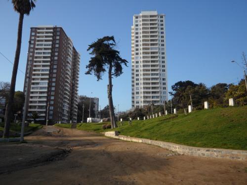 a dirt road with two tall buildings and a palm tree at Vista y Mar in Valparaíso
