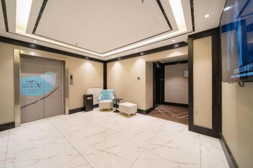 Habitación grande con TV y sillas. en Xana Hotelle Jinan Daminghu North Gate, en Jinan