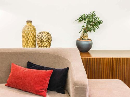 a couch with two vases and a potted plant at Hotel Ibis Coimbra Centro in Coimbra