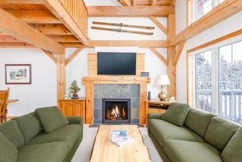 a living room with two green couches and a fireplace at Alpine Timbers 2 Luxury Chalet with Hot Tub in Big White