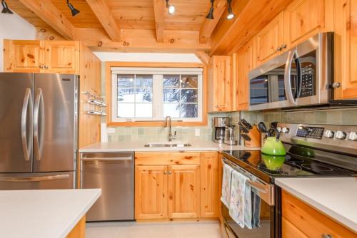 a kitchen with wooden cabinets and a stainless steel refrigerator at Alpine Timbers 2 Luxury Chalet with Hot Tub in Big White