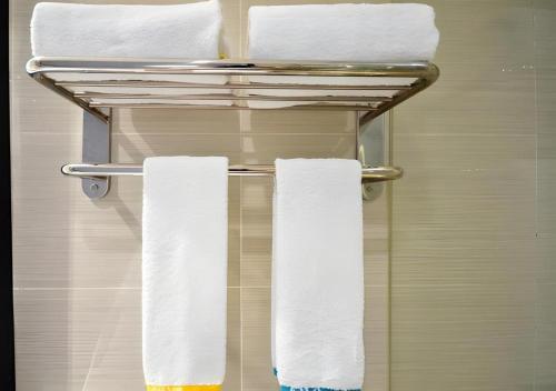 City Comfort Inn Jingzhou Hongxing Road Food Street في Shashi: رف مناشف في الحمام مع مناشف