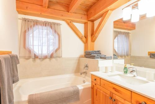 ビッグ・ホワイトにあるAlpine Timbers 2 Luxury Chalet with Hot Tubの白い浴槽と洗面台のあるバスルーム