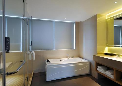 City Comfort Inn Nanning Xingning District Government Maternal and Child Health Hospital في نانينغ: حمام مع حوض استحمام ودش ومغسلة