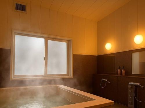 a large bathroom with a tub and a window at 安比高原ロッジタンデム in Wada