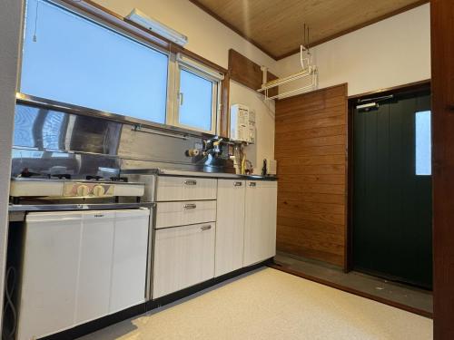 a kitchen with white cabinets and a large window at 安比高原ロッジタンデム in Wada