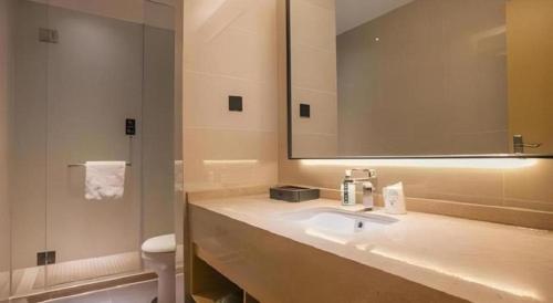 City Comfort Inn Wuhan Tianhe Airport Outlets في ووهان: حمام مع حوض و مرآة و مرحاض