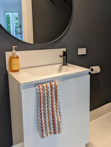 a bathroom sink with a towel hanging from it at Private Garden Studio - Walk to Beach in Byron Bay