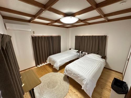 zwei Betten in einem Zimmer mit Holzboden in der Unterkunft MIYABI stay house in Tamana