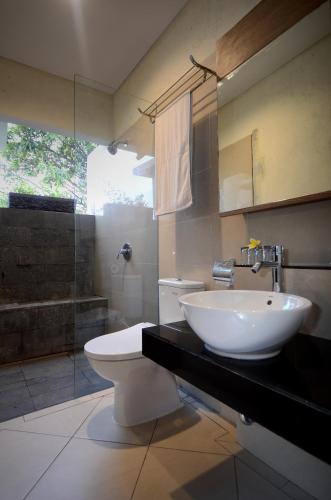 a bathroom with a sink and a toilet and a shower at Bali Breezz Hotel in Jimbaran