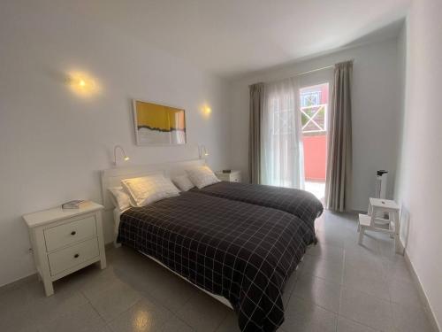 Apt. El Guirre Nº 8 - bajo في La Playa Calera: غرفة نوم بسرير وبطانية منقوشة ونافذة