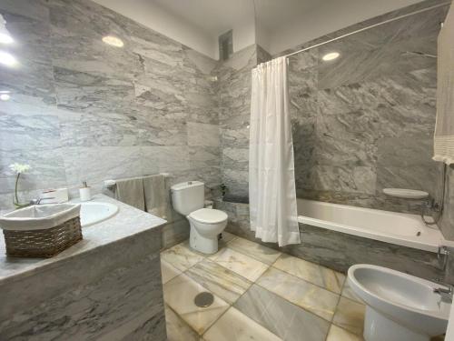 Apt. El Guirre Nº 8 - bajo في La Playa Calera: حمام مع حوض ومرحاض وحوض استحمام