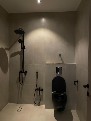 e bagno con doccia e servizi igienici neri. di شاليه لوسيندا a Baljurashi
