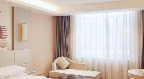 a hotel room with a chair and a window at Vienna Hotel Shandong Qufu Sankong Landscape in Qufu