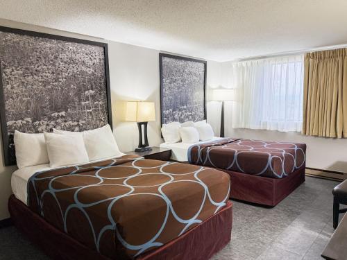 a hotel room with two beds and a couch at Super 8 by Wyndham Williston ND in Williston