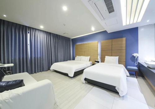 um quarto de hotel com duas camas e um sofá em Arieti A em Gimhae