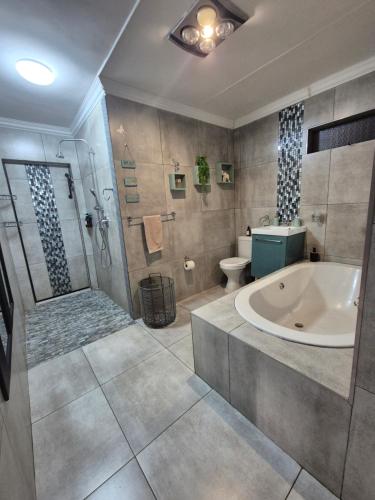 uma casa de banho com uma banheira, um chuveiro e um WC. em Bosveld In Die Stad Lodge em Alberton