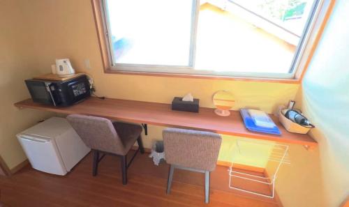 a desk with two chairs and a microwave and a window at 白浜の宿梅 別館 in Shirahama