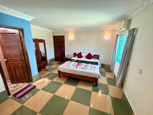 een slaapkamer met een bed en een geruite vloer bij SOMA Villa in Phumĭ Réach Born