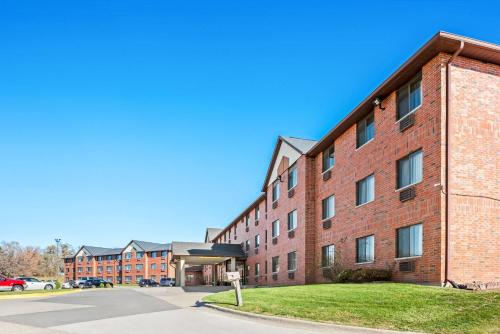 a large red brick building with a parking lot at Days Inn & Suites by Wyndham Des Moines Airport in Des Moines