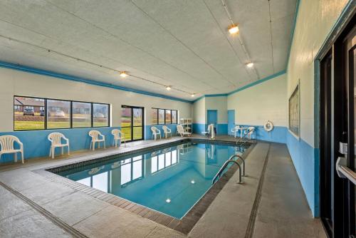 a swimming pool with chairs and tables in a building at Days Inn & Suites by Wyndham Des Moines Airport in Des Moines