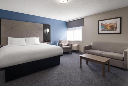 a hotel room with a large bed and a couch at Baymont by Wyndham Davenport in Davenport