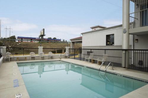 a swimming pool with chairs next to a building at Days Inn by Wyndham Augusta Fort Eisenhower in Augusta