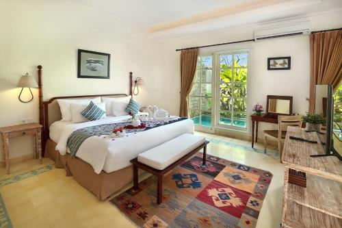 a bedroom with a king sized bed and a balcony at Maison at C Boutique Hotel & Spa Seminyak in Seminyak