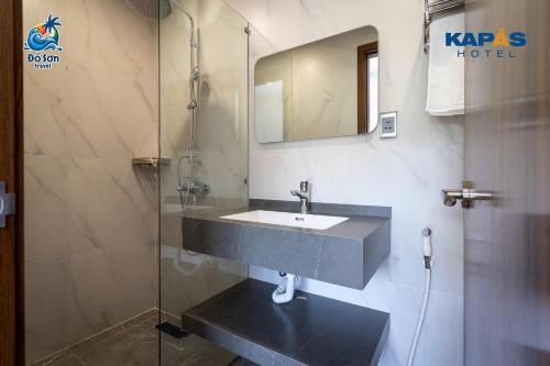 a bathroom with a sink and a glass shower at Kapás Hotel in Hai Phong