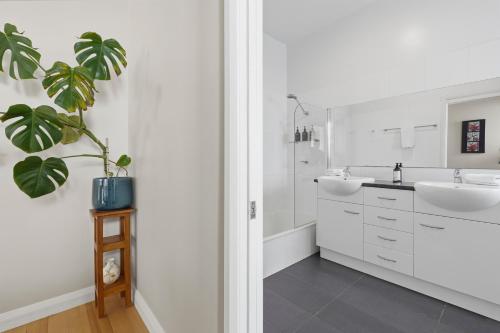 a white bathroom with two sinks and a plant at Poets View - 3 Bedroom House in West Hobart
