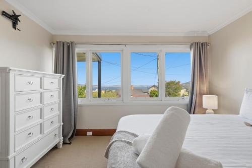 a bedroom with a bed and a large window at Poets View - 3 Bedroom House in West Hobart