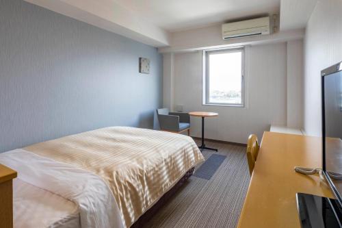 a hotel room with a bed and a desk and a window at Comfort Inn Yokaichi in Higashiomi