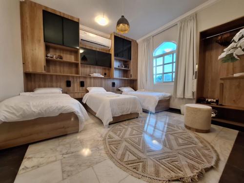 a bedroom with three beds and a large window at East Coast Vacation Homes in Kalbā