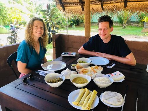 a man and a woman sitting at a table with food at Lotus cool hotel and restaurant in Ibbagomuwa