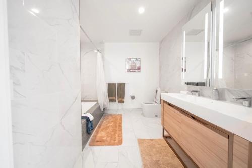a white bathroom with a sink and a toilet at Lavish High-Rise 2bed Apt in the Hearth of Downtown LA in Los Angeles