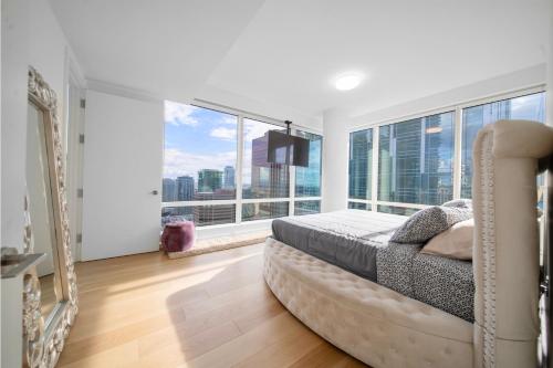 a bedroom with a bed and large windows at Lavish High-Rise 2bed Apt in the Hearth of Downtown LA in Los Angeles