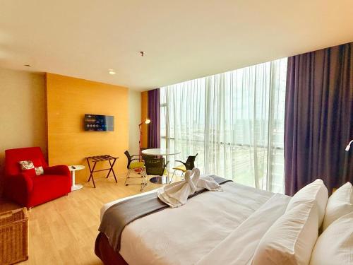 a hotel room with a bed and a red chair at NuEmpire Subang Suite - Empire Hotel in Subang Jaya